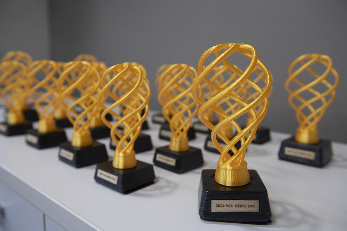 A photo of 19 black and yellow 3D printed trophies. 