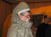 Decontamination Exercise. Dr. Ruddy Rose, director of the VCU Poison Center, even has enough room for eyeglasses in the Level C protection suit worn during a decontamination drill. Health professionals working outside the hospital would wear the Level C suit during initial patient encounters. The decontamination tent is in the background.