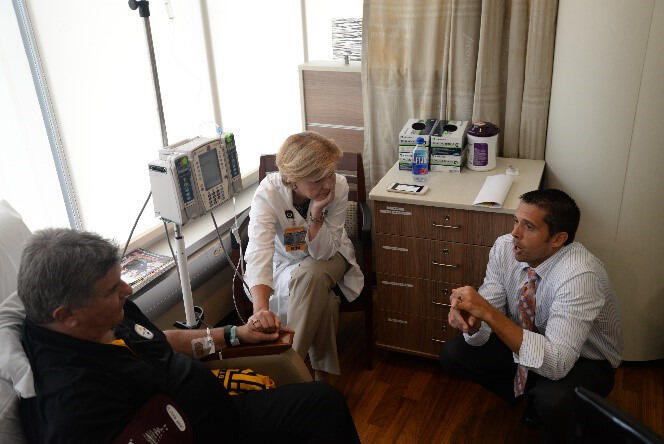 Scott Vota (right), speaks with Jerry and Sue Creehan on Aug. 23 as Jerry receives an infusion to treat ALS.
