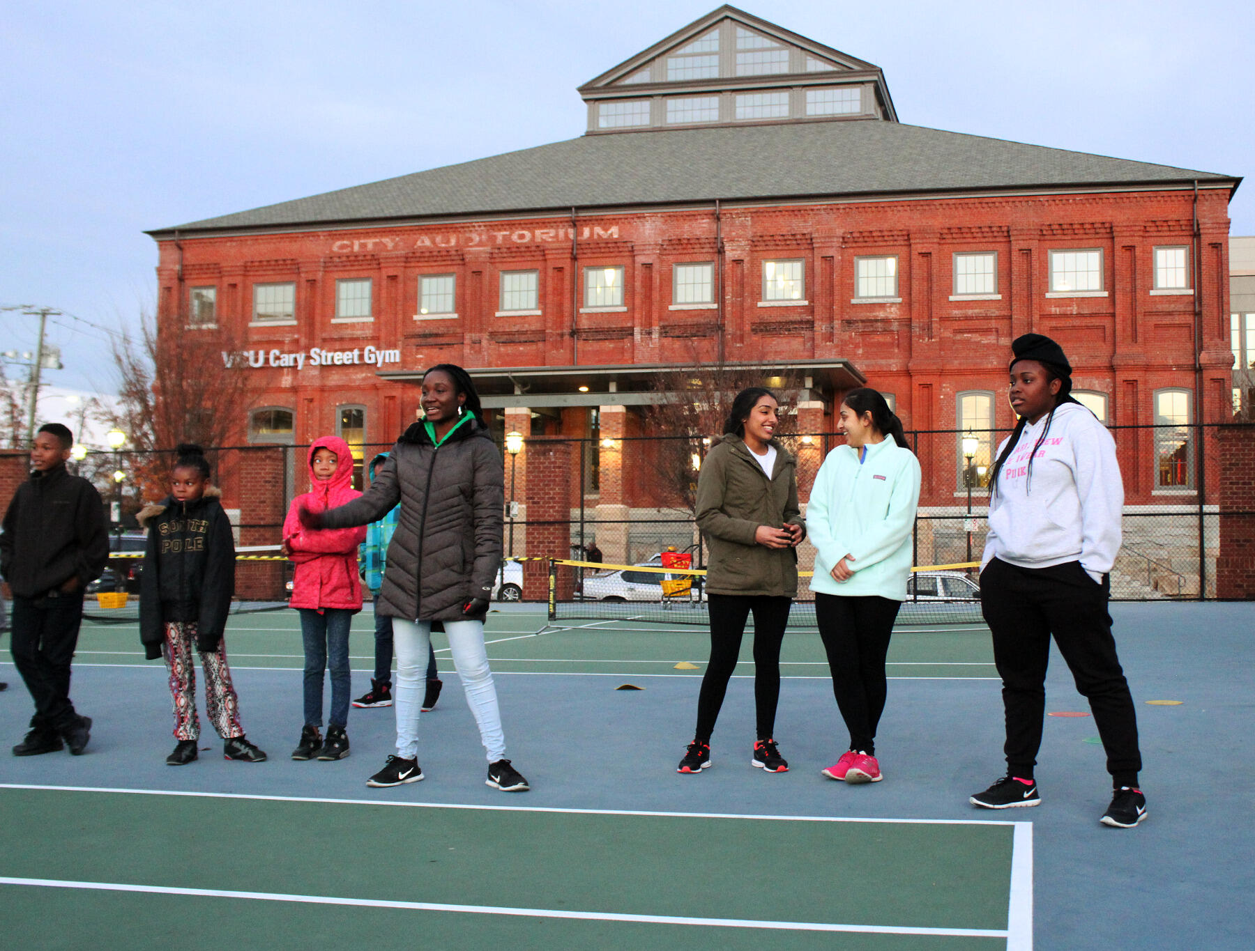 Kids, staff and volunteers take part in a team exercise before starting tennis practice.