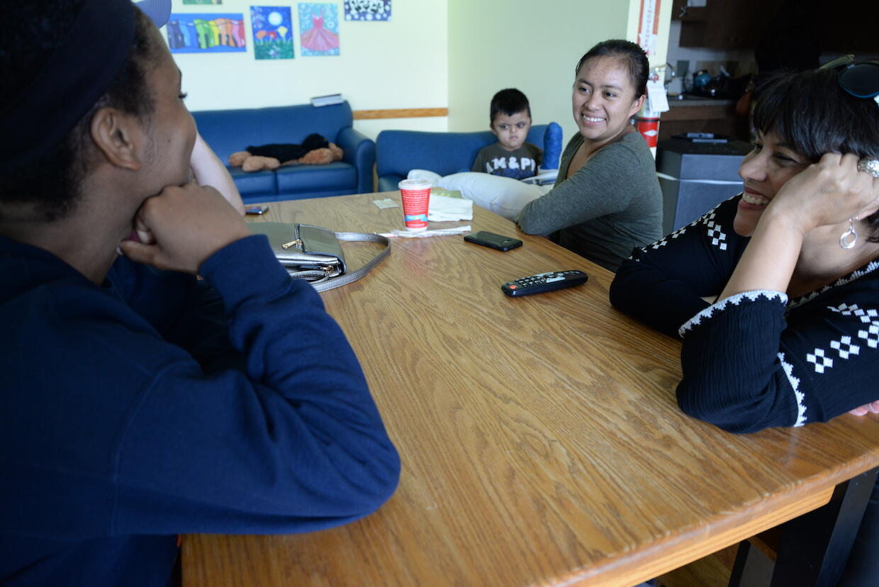 VCU student Naomi Lauture (left) and Spanish professor Anita Nadal (right) talk with 5-year-old Saul and his mother Evelin Sazo at the Doorways hospitality house. (Brian McNeill)