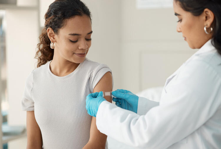A photo of a doctor putting a bandaid on a woman's arm. 