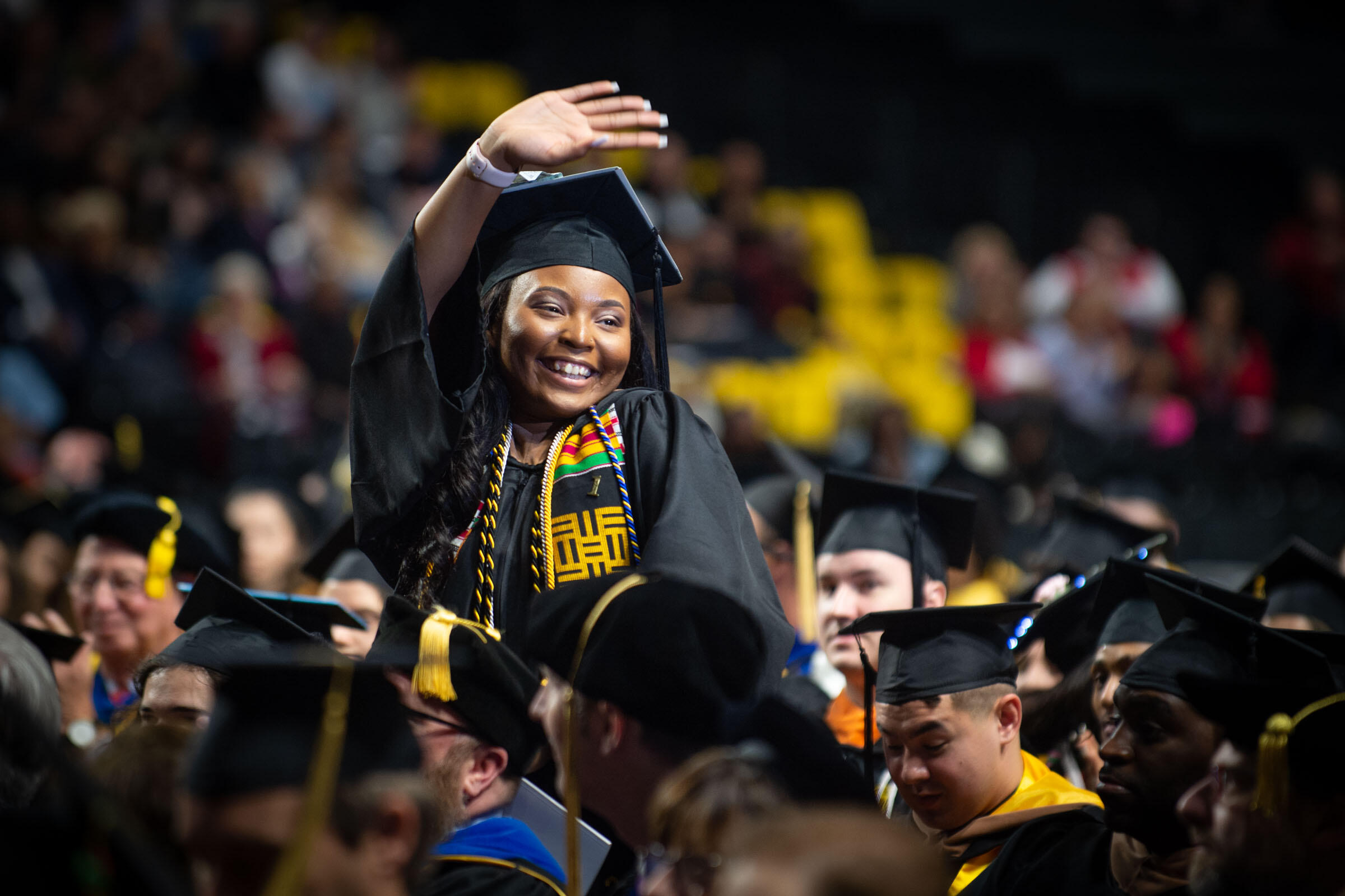 A student standing and waving during the commencement ceremony.