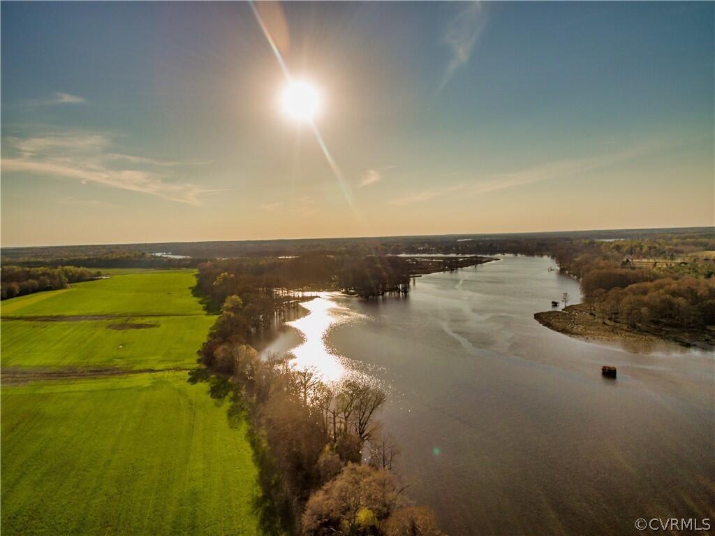 An aerial view of the James River next to a field and line of trees