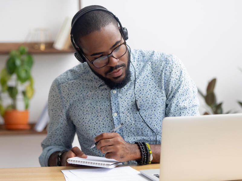 A headphones-wearing person working on a laptop computer.