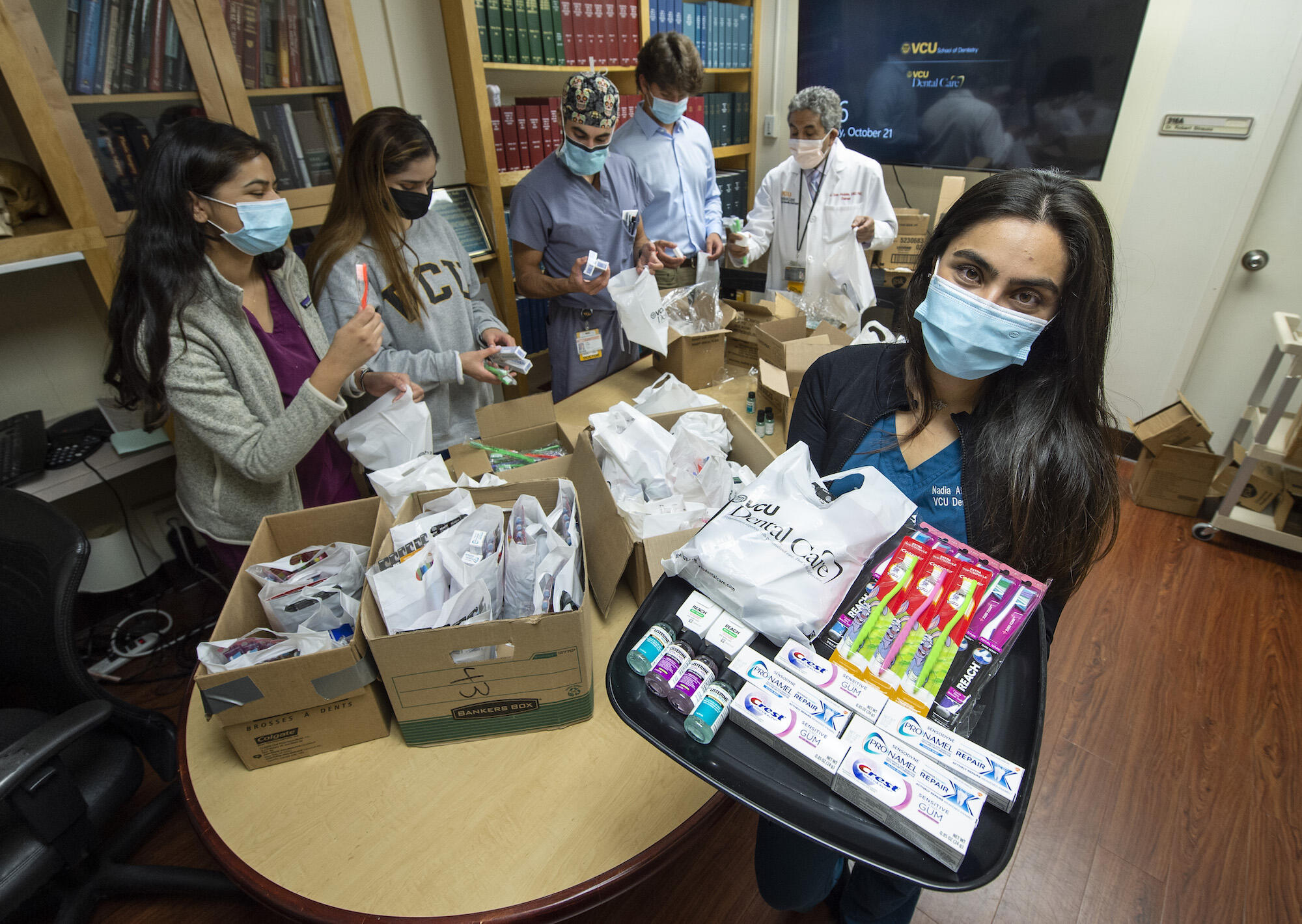 Nadia Abdul-Ghafoor, far right, holding a dental supply kit in a conference room surrounded by classmates and faculty from the VCU dental school