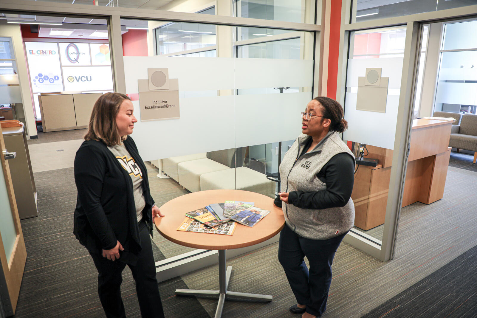 Malorie Yeaman, Title IX coordinator and director of outreach and support at VCU, speaks with Cleopatra Magwaro, associate vice president of institutional equity and interim Americans with Disabilities Act coordinator. They are standing and talking to each other across a small table.