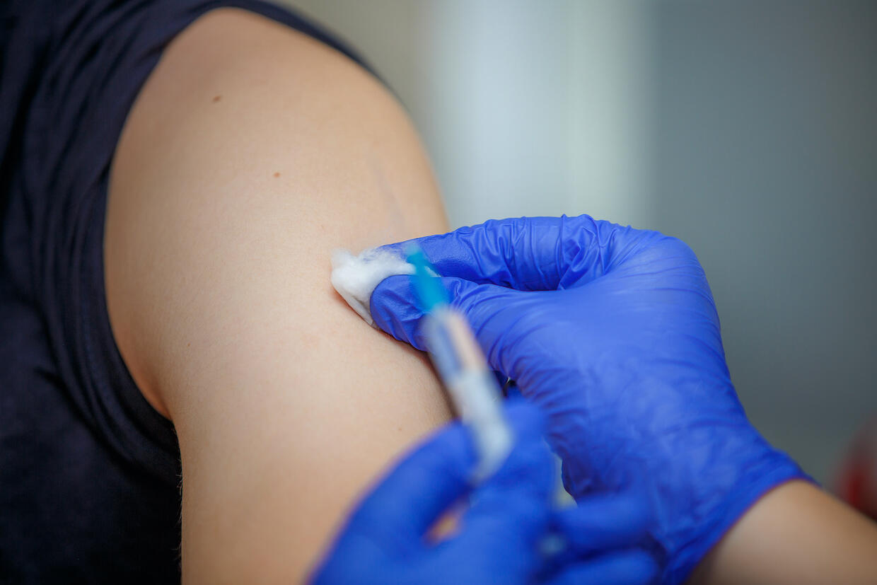 close-up image of an arm and a flu shot vaccine