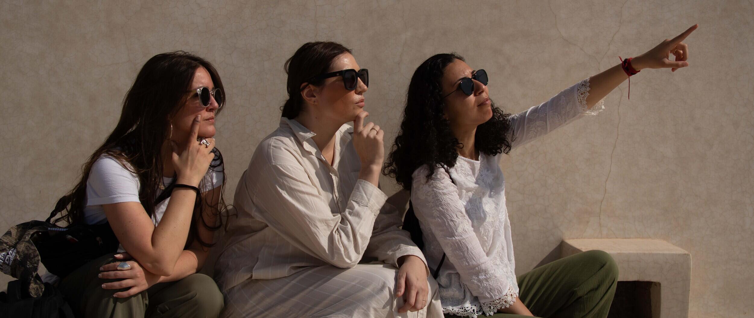 A photo of three people sitting and looking to the right.