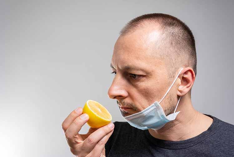 Man wearing a mask smells a lemon