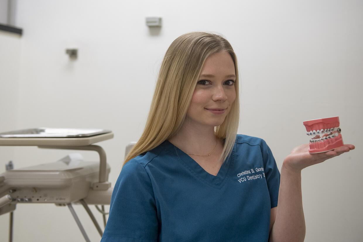 Christina Gordon, a VCU dental student, holds a model of human teeth wearing braces.