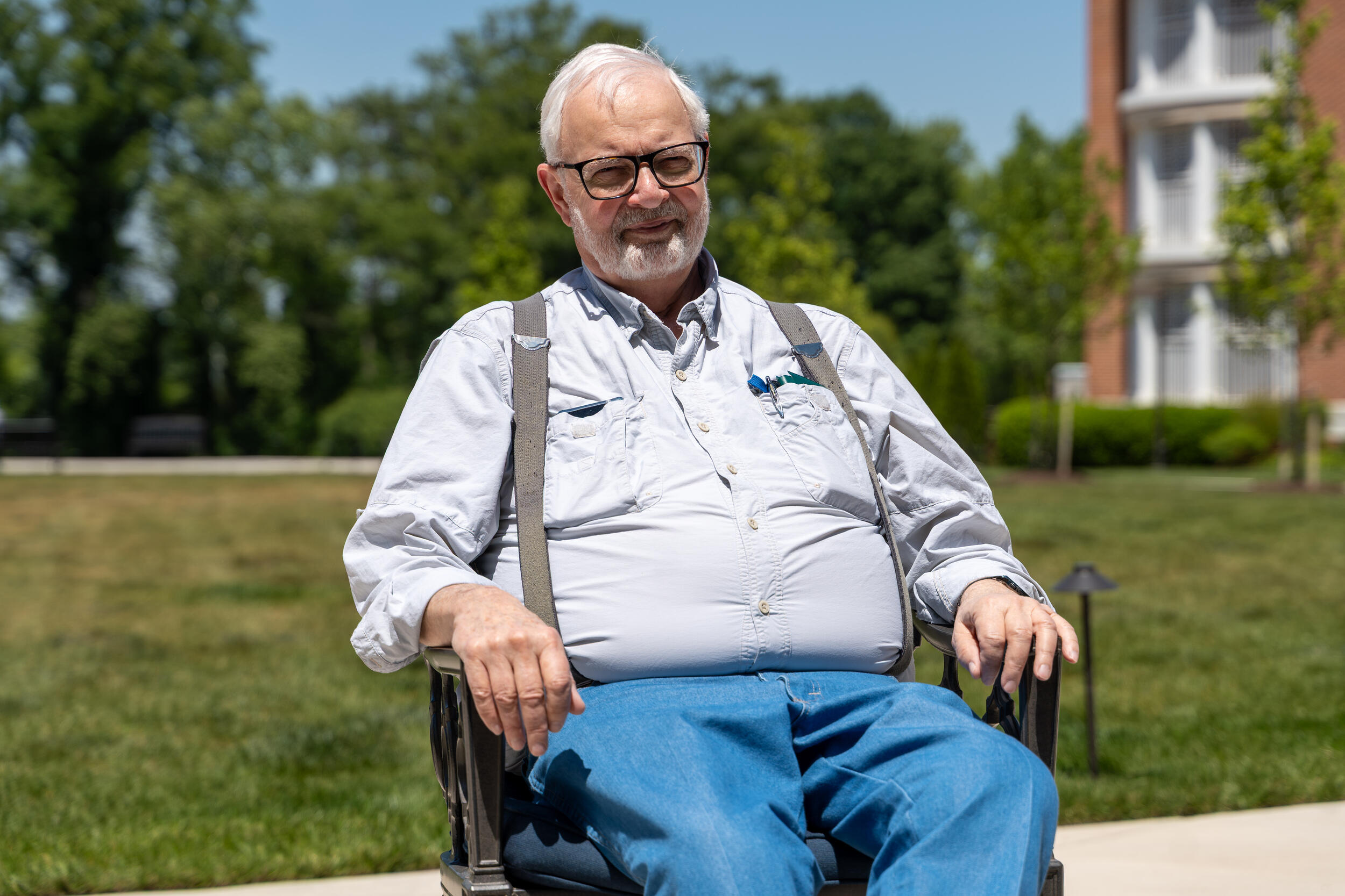 A photo of a man sitting in a wheelchair outside. 