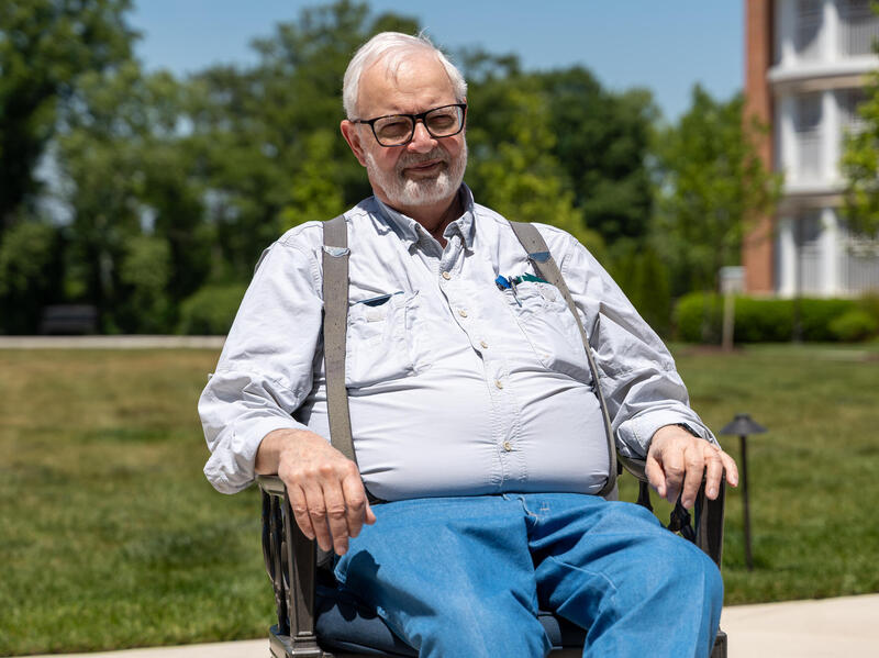 A photo of a man sitting in a wheelchair outside. 