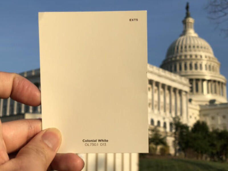 Paint chip held up in front of large building.