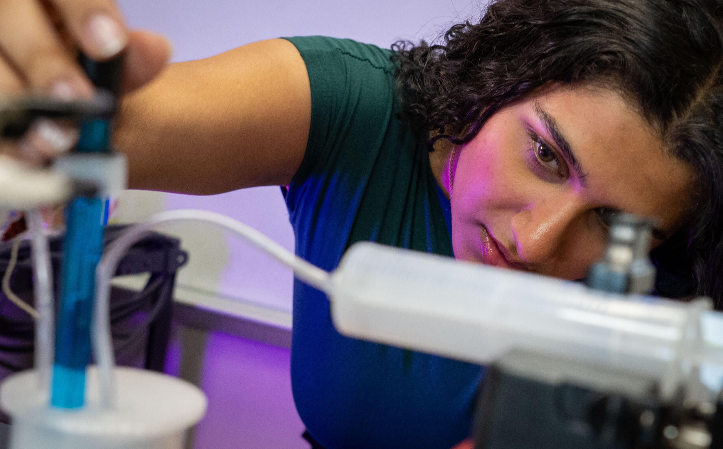 A photo of a woman looking closely at scientific equipment. 