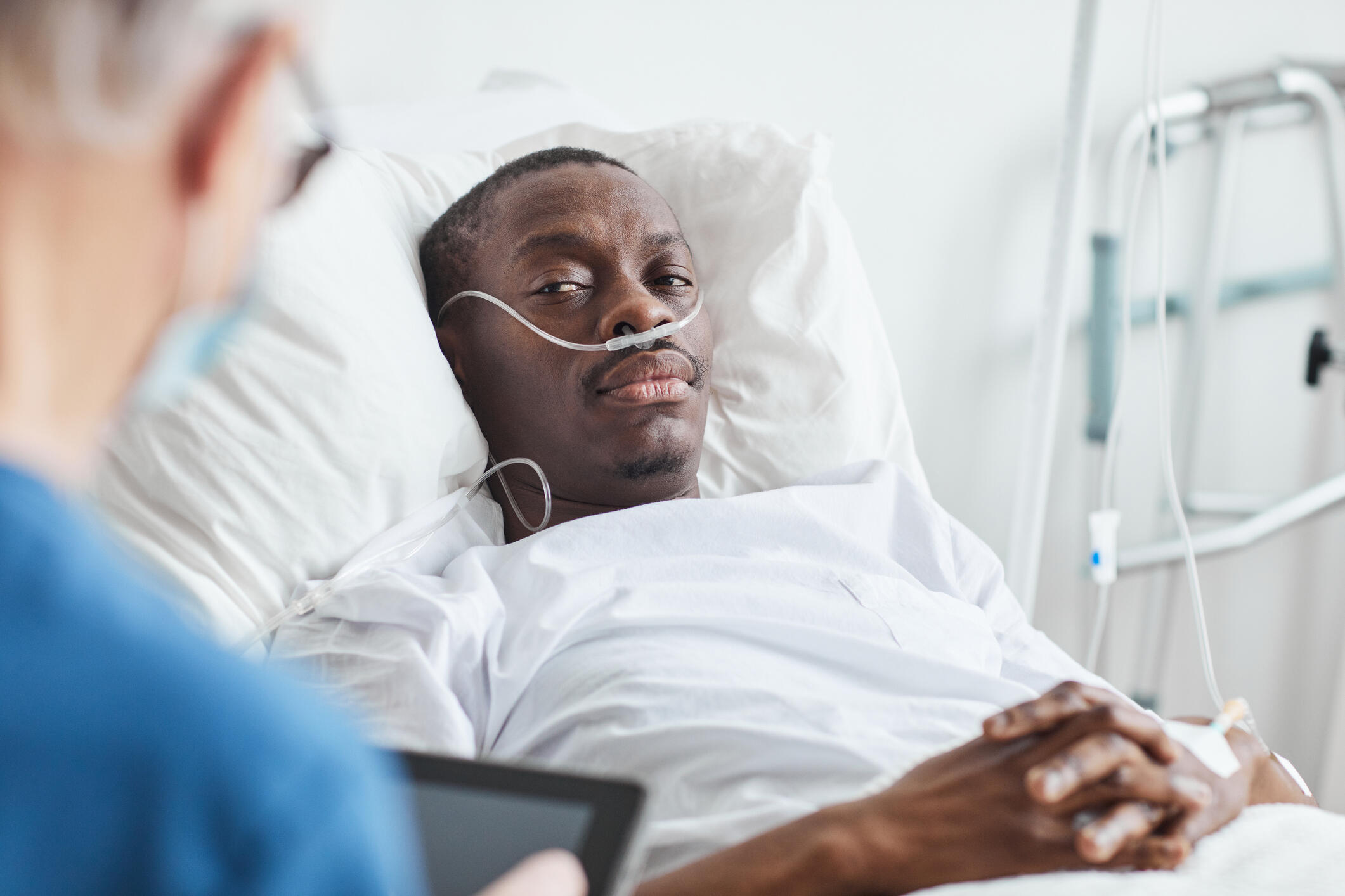 A man sitting in a hospital bed looking at a healthcare provider 