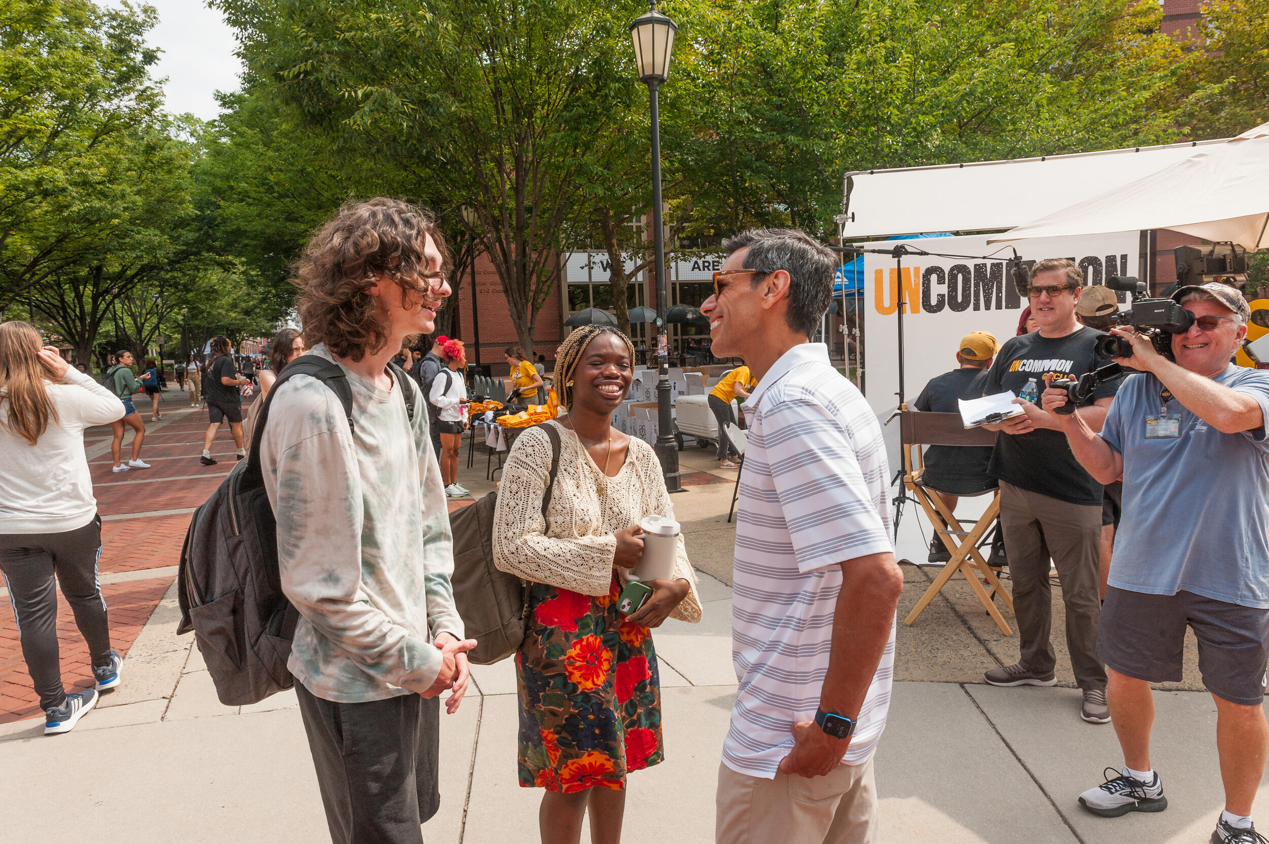 Three people talking to each other on a sidewalk 