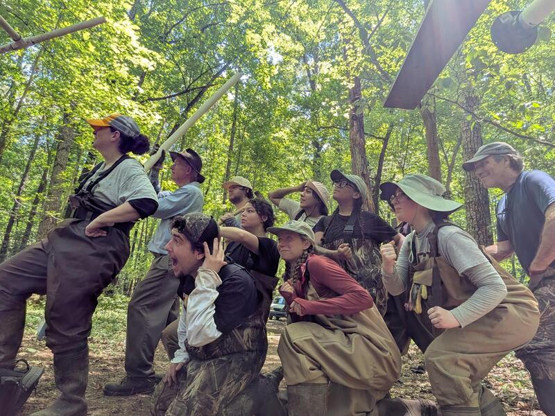 A group photo of 10 people in the woods looking ot the left. 