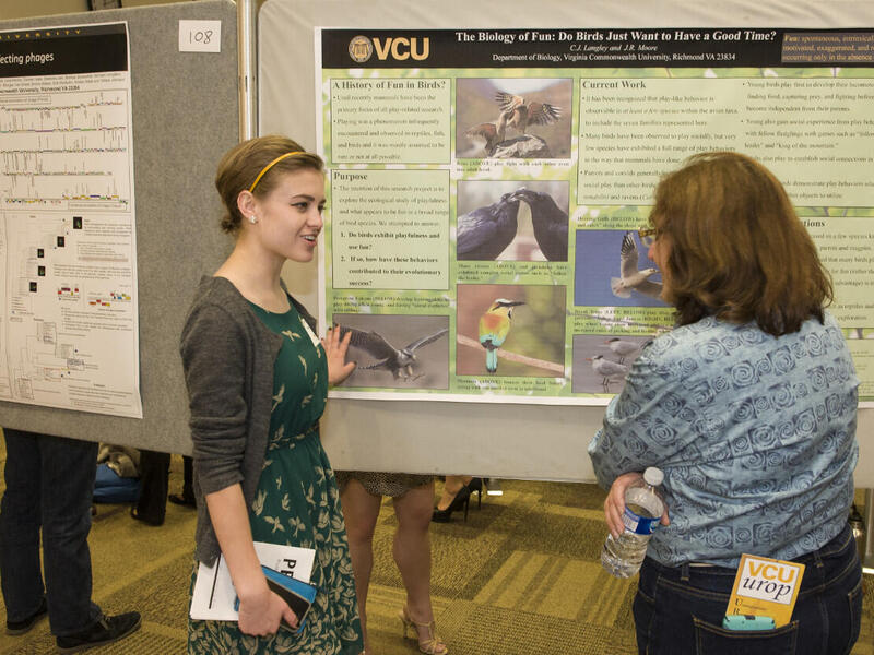 Two women stand in front of a poster presentation.