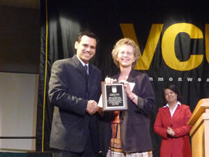 Photo- Pride Ambassador Award Ceremony- Barbara Judy: From left: VCU President Michael Rao congratulates Pride Ambassador honoree Barbara Judy of Academic Affairs, while Marquita Aguilar, chair of VCU Staff Senate activities and events, applauds in the background. Photos by Mike Porter, VCU Communications and Public Relations