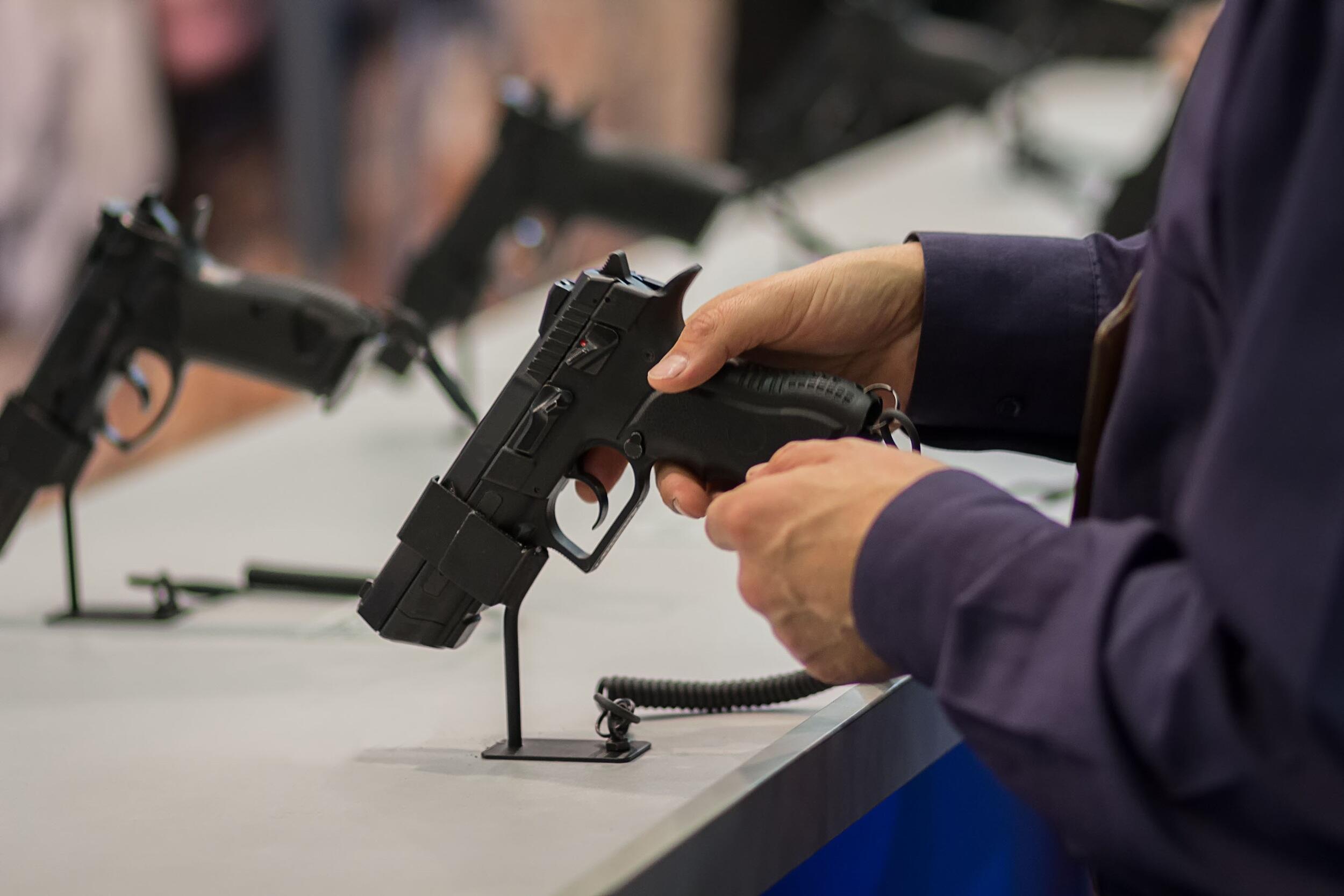 A person holding a handgun at a gun show.