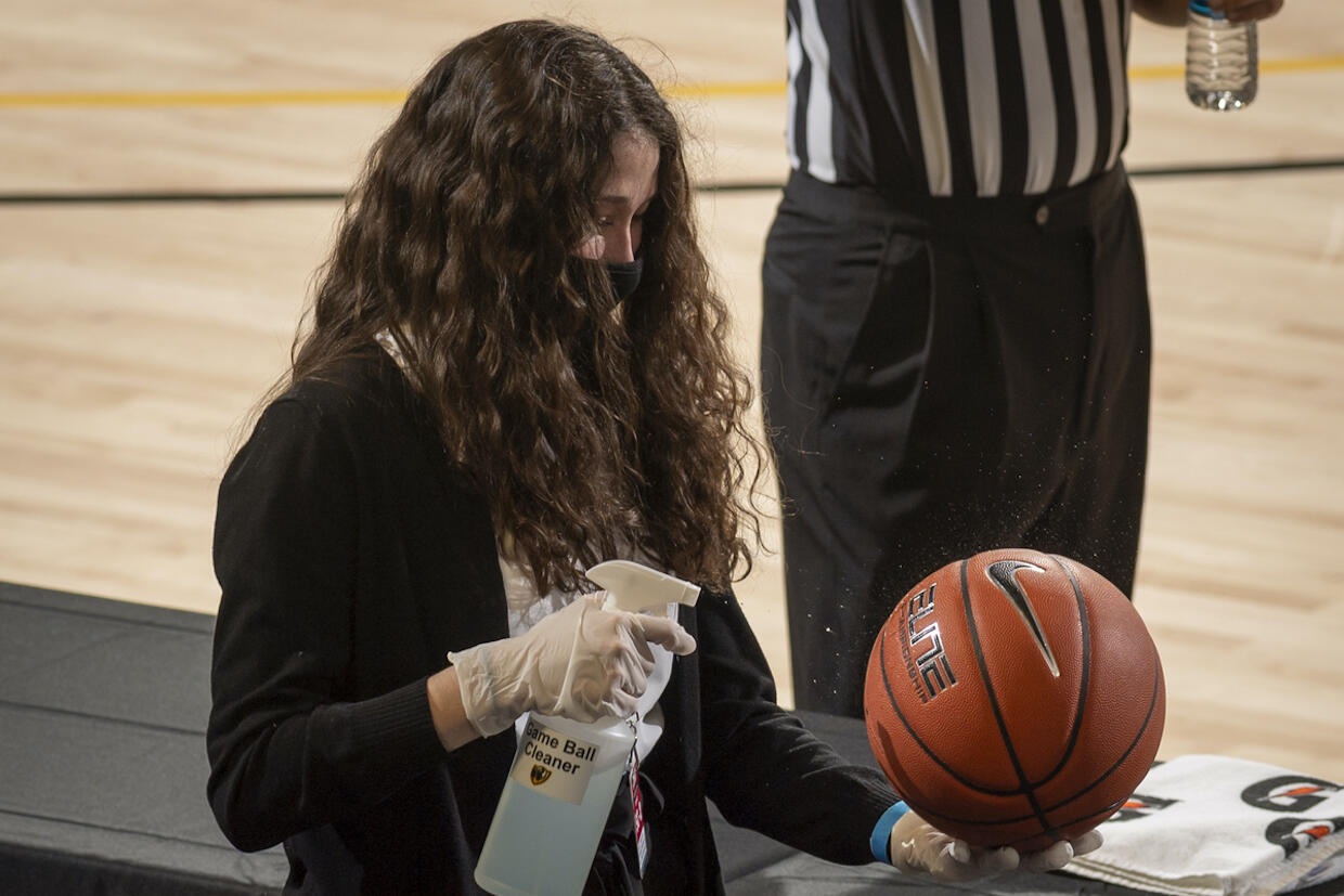 A VCU employee cleans a basketball during a game.