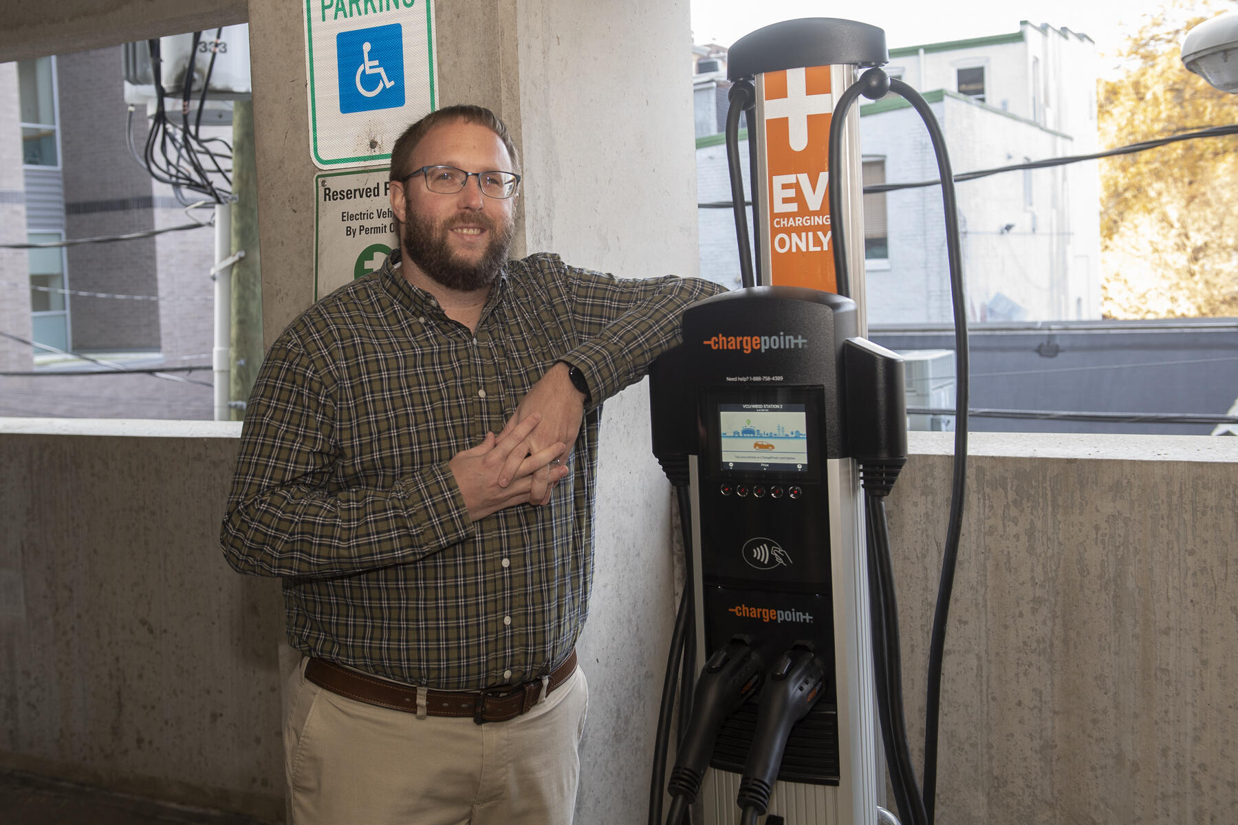 Josh Stone standing next to an electric vehicle charging station
