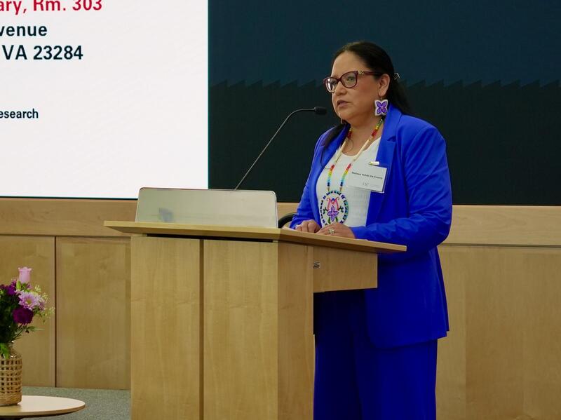 A photo of a woman standing behind a podium and speaking. 
