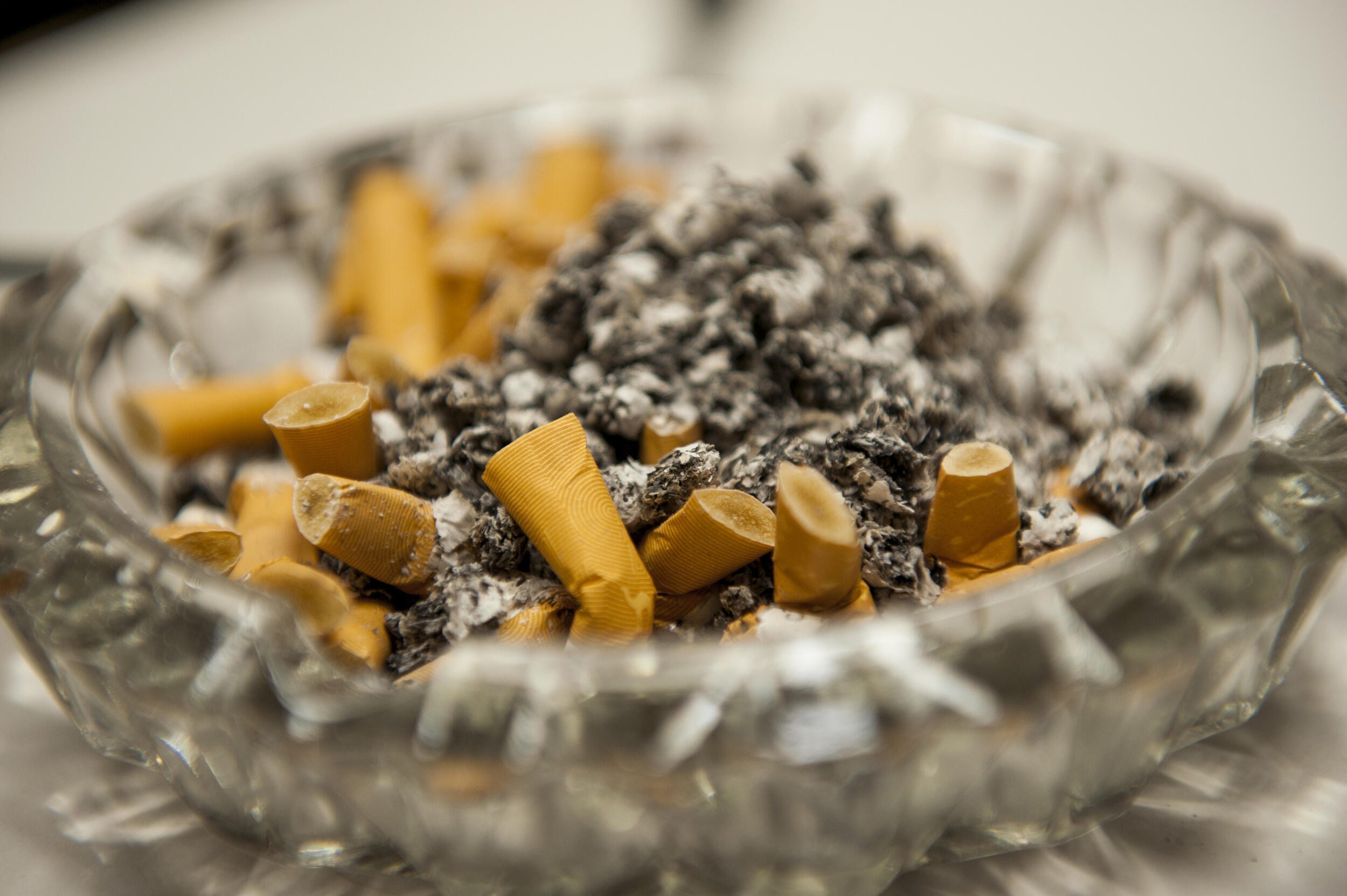 A glass ashtray filled with cigarette butts and ash