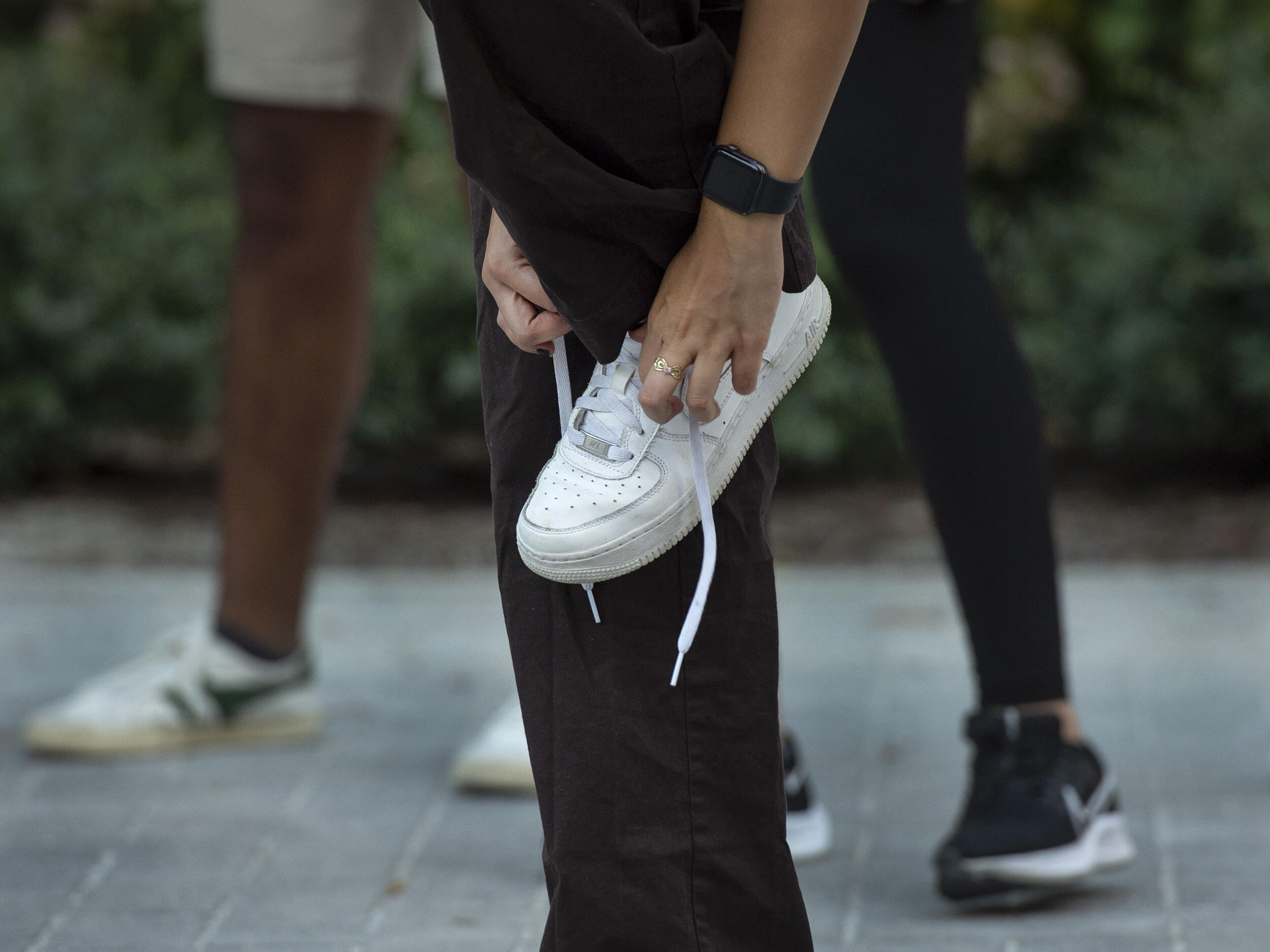 Two hands lacing up a white sneaker 