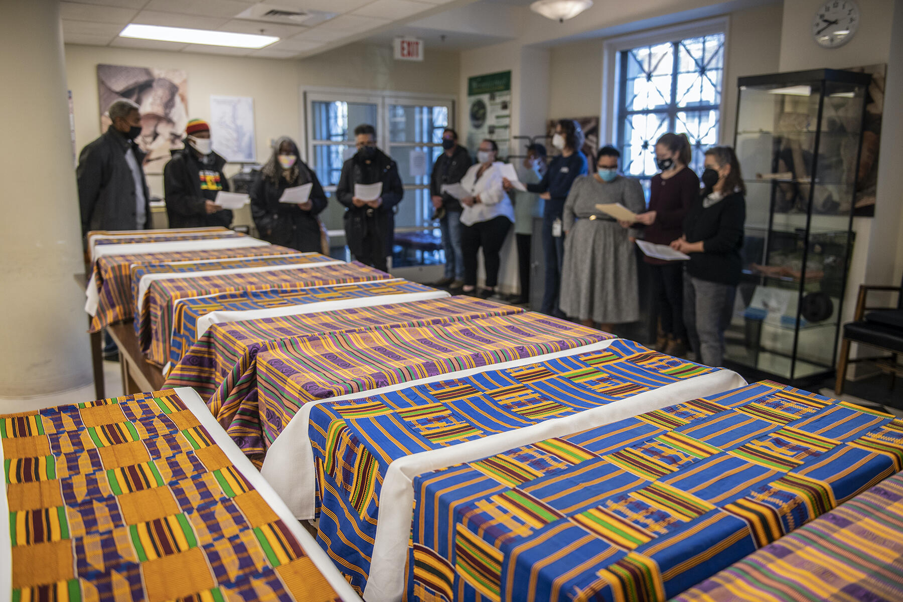 People standing around boxes covered with african fabric. 