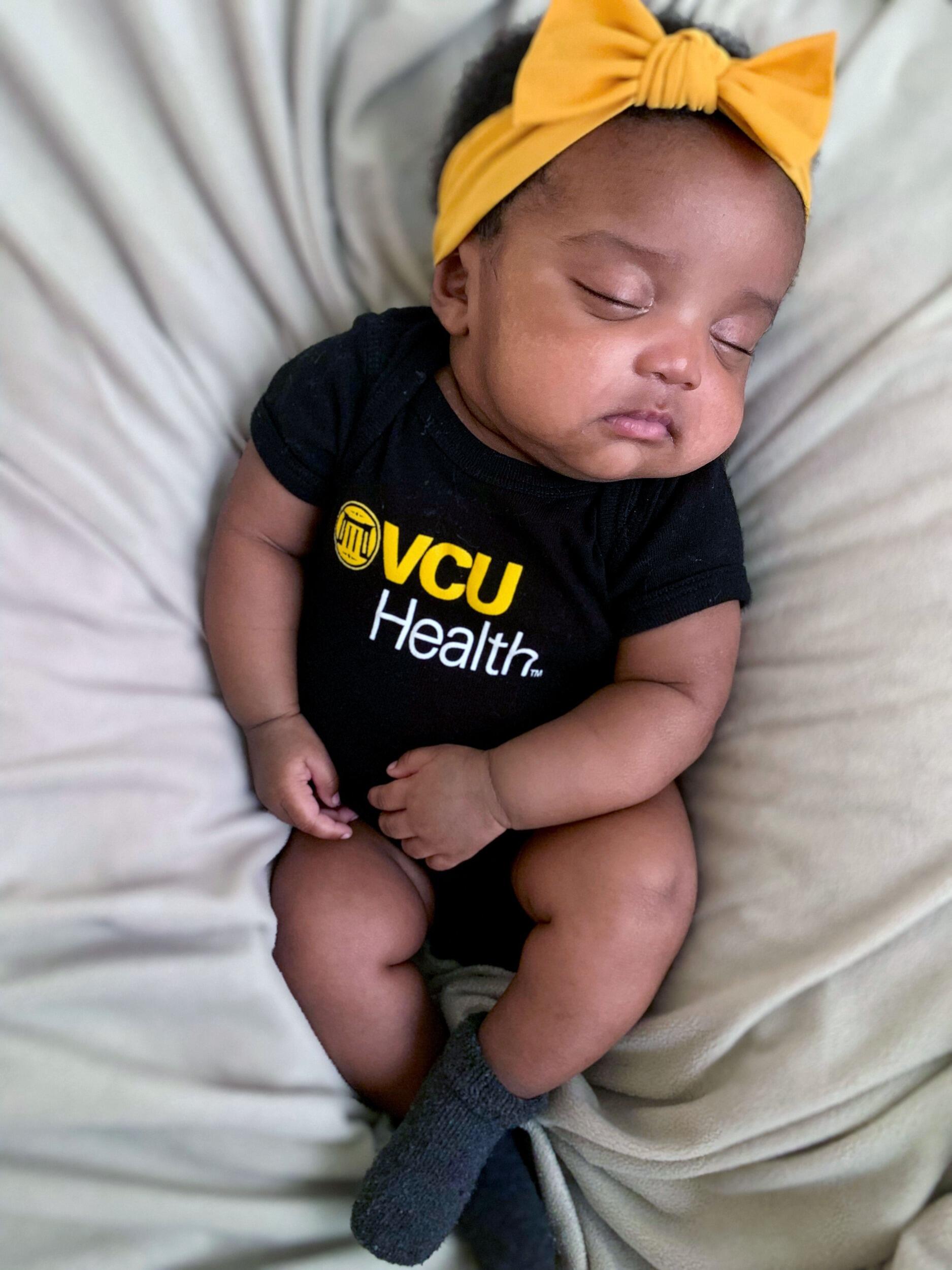 A newborn wearing a VCU Health onesie.