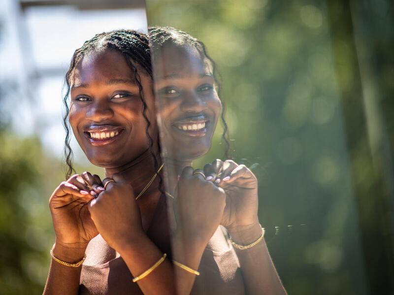 A photo of a woman standing next to a reflection of herself. 