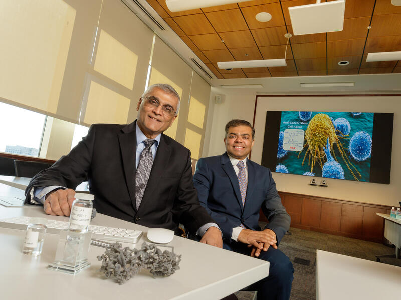 A photo of two men sitting behind a table. 