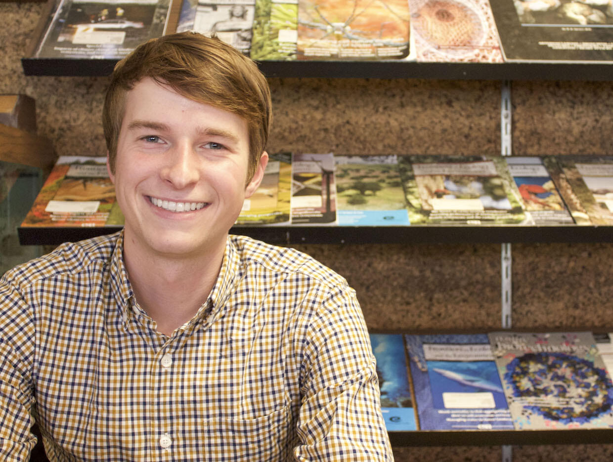 Chase Phillips poses in front of rows of magazines.