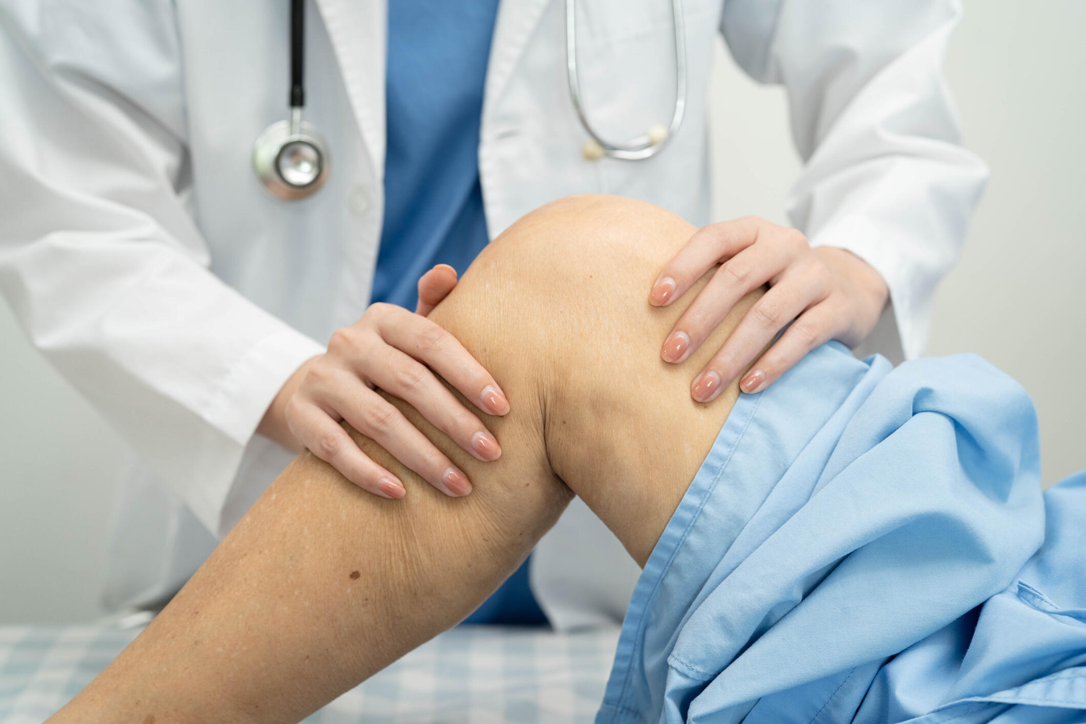 A doctor examines a knee, reflecting an examination related to knee replacement surgery.