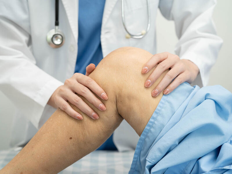 A doctor examines a knee, reflecting an examination related to knee replacement surgery.