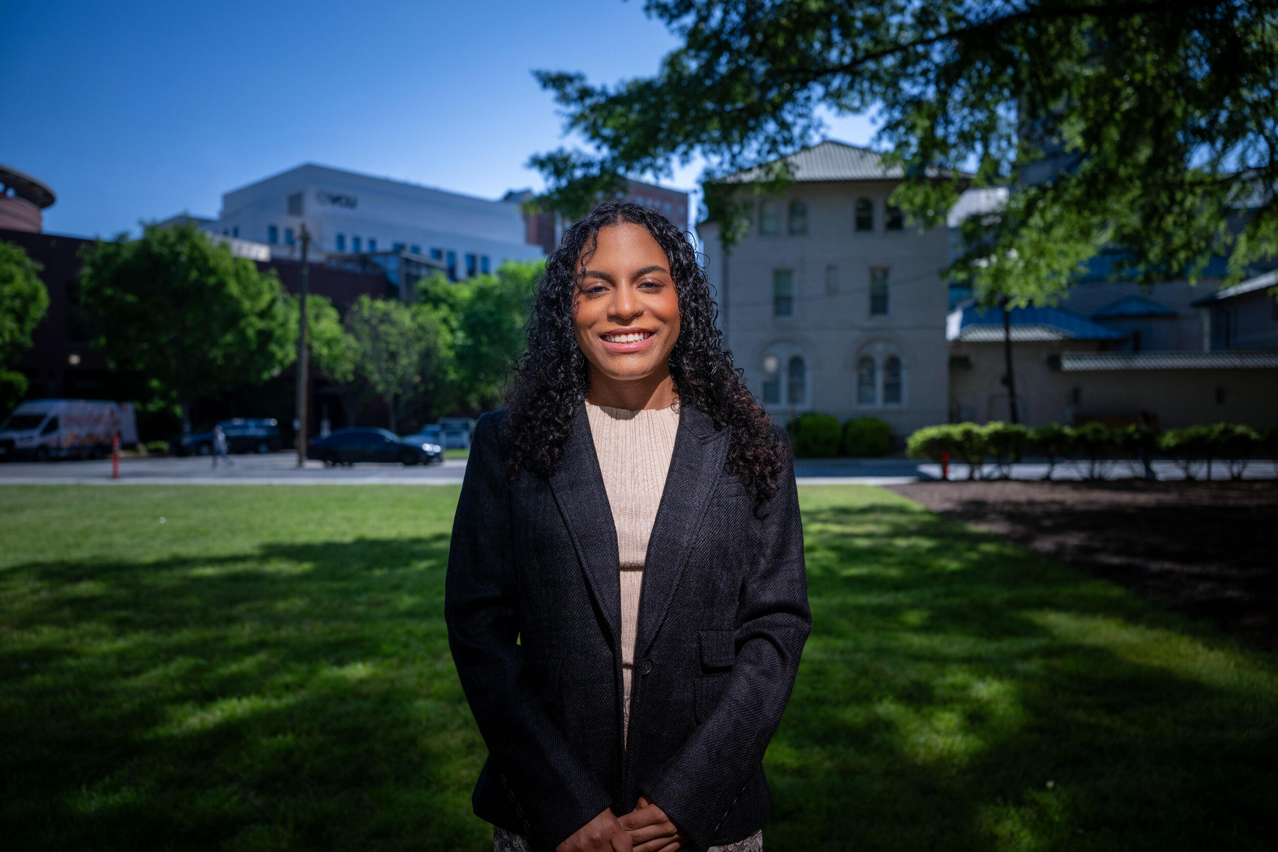 A woman in a blazer stands on a lawn.