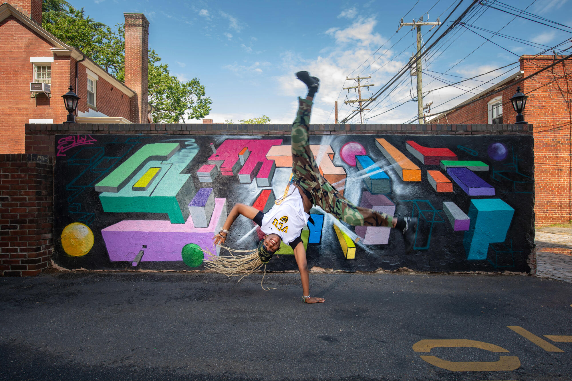 A photo of a person breakdancng in front of a mural. 