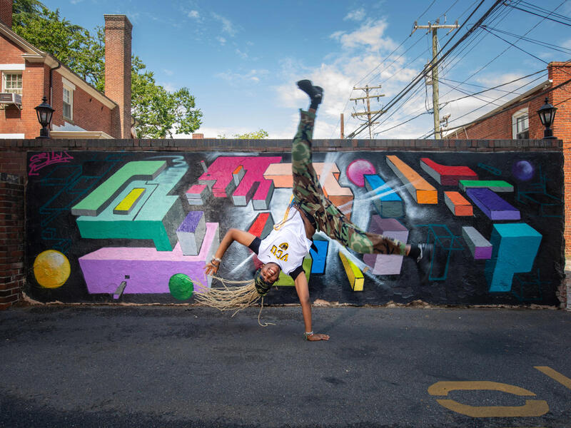 A photo of a person breakdancng in front of a mural. 