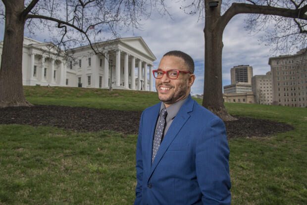 Man in blue suit and red glasses in front of the Virginia State Capitol.