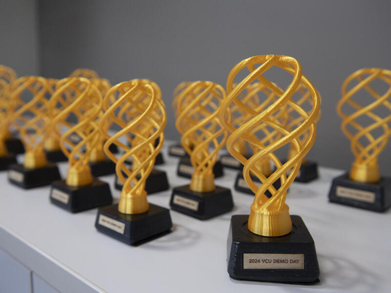 A photo of 19 black and yellow 3D printed trophies. 