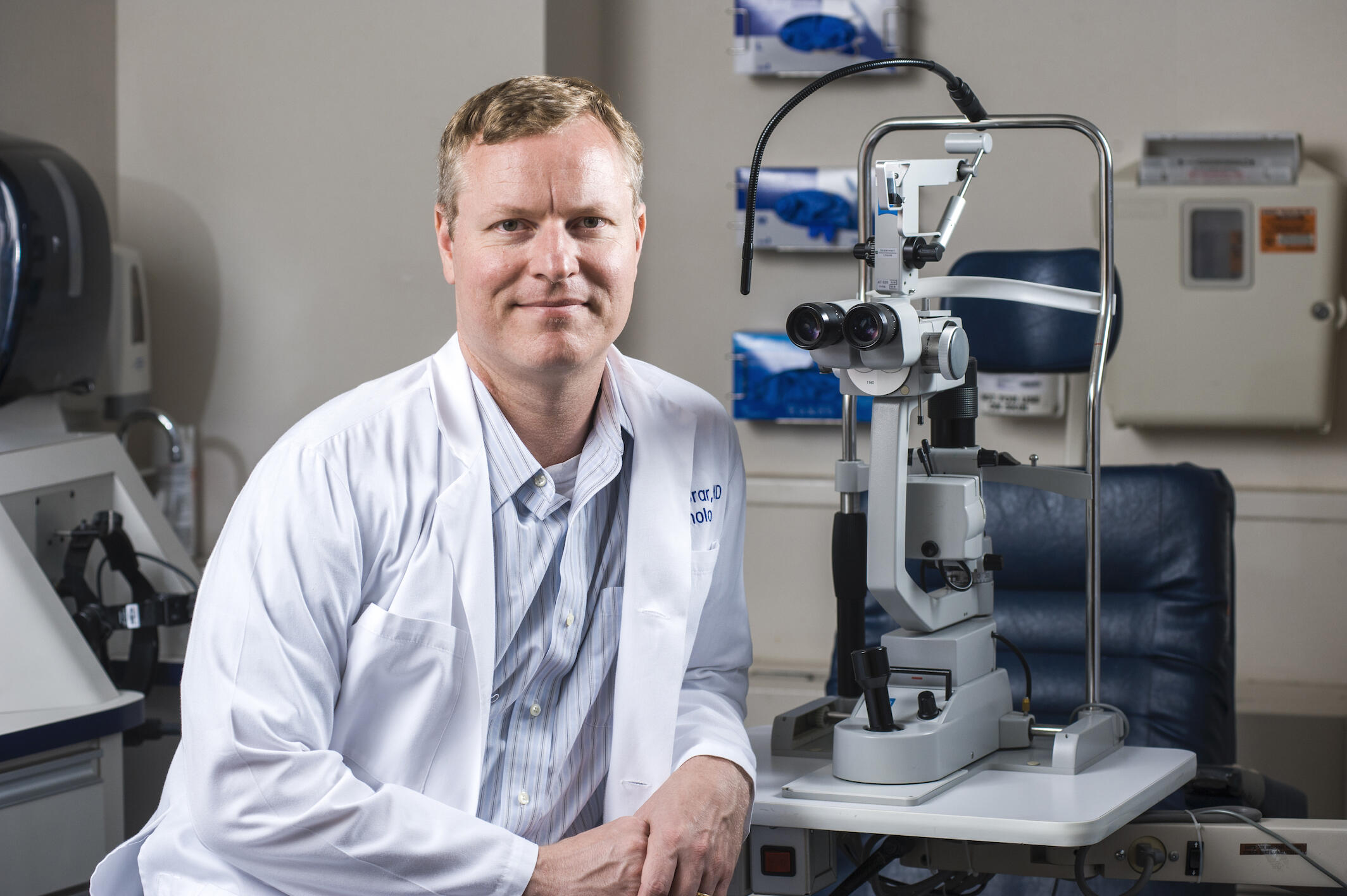Christopher Leffler seated next to a microscope.