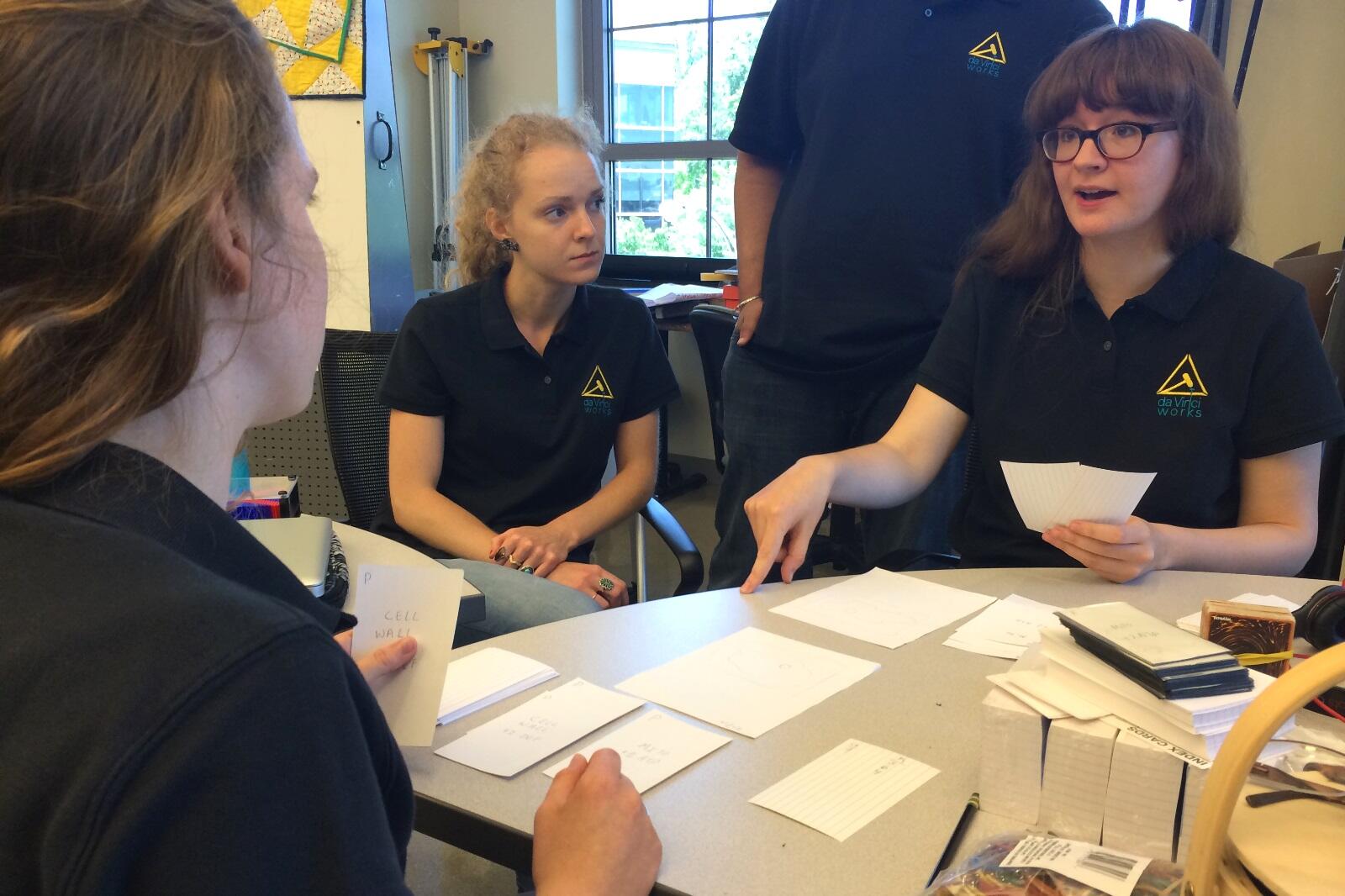 Katherine Marchese, Jessica Bishop and Gwendolyn Wood test out a card game, similar to Magic: The Gathering, that aims to teach people about mitochondria and cellular biology. 