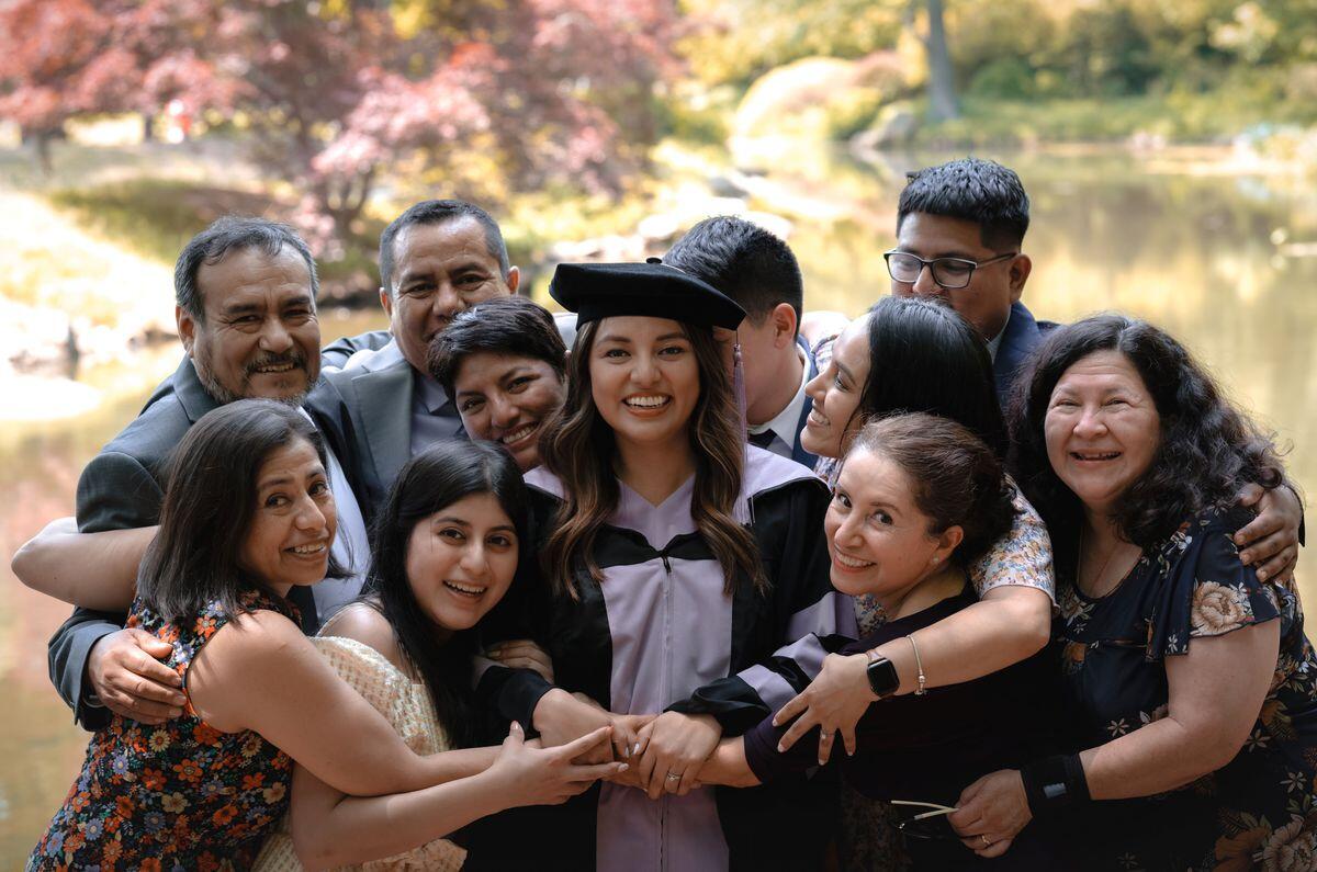 A group photo of a family hugging a woman wearing a graduation cap and gown. 