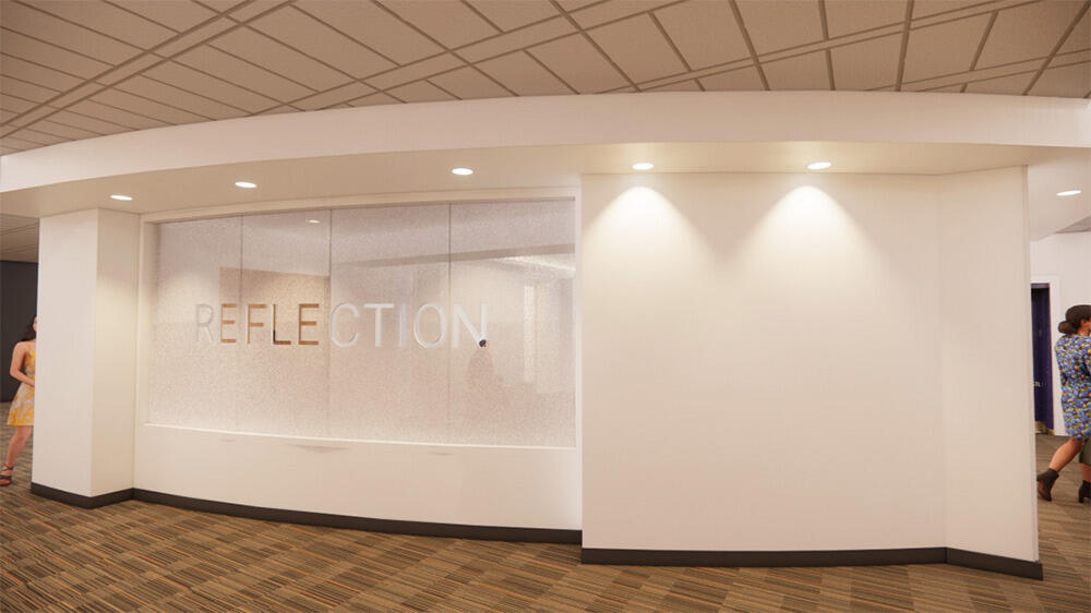 A white wall with a glass paneling that has the word \"REFLECTION\" written on in in white lettering. 