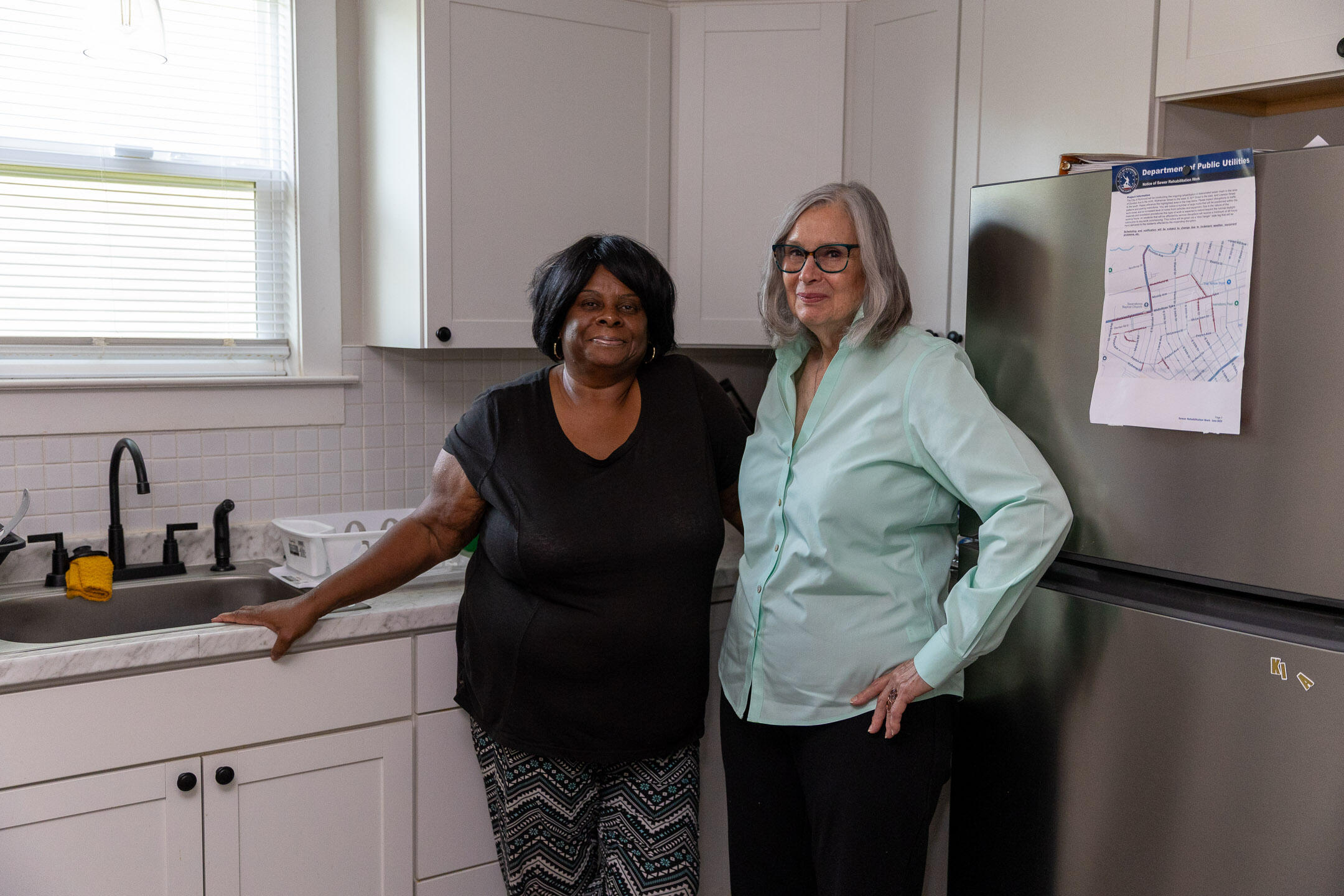 A photo of two women standing in a kitchen. 