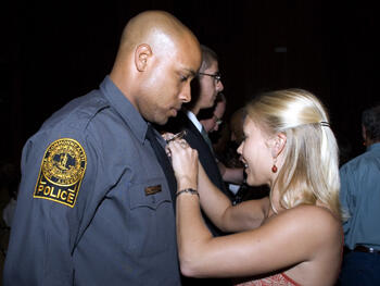 VCU Police Academy graduates received a badge from family members, friends and loved ones. Here, graduate Jacelle Winston (left) receives his badge at the conclusion of the VCU Police Basic Academy graduation exercises.  Winston also received a physical fitness award. Photo by: Melissa Gordon, VCU Office of University Communications and Public Relations.
