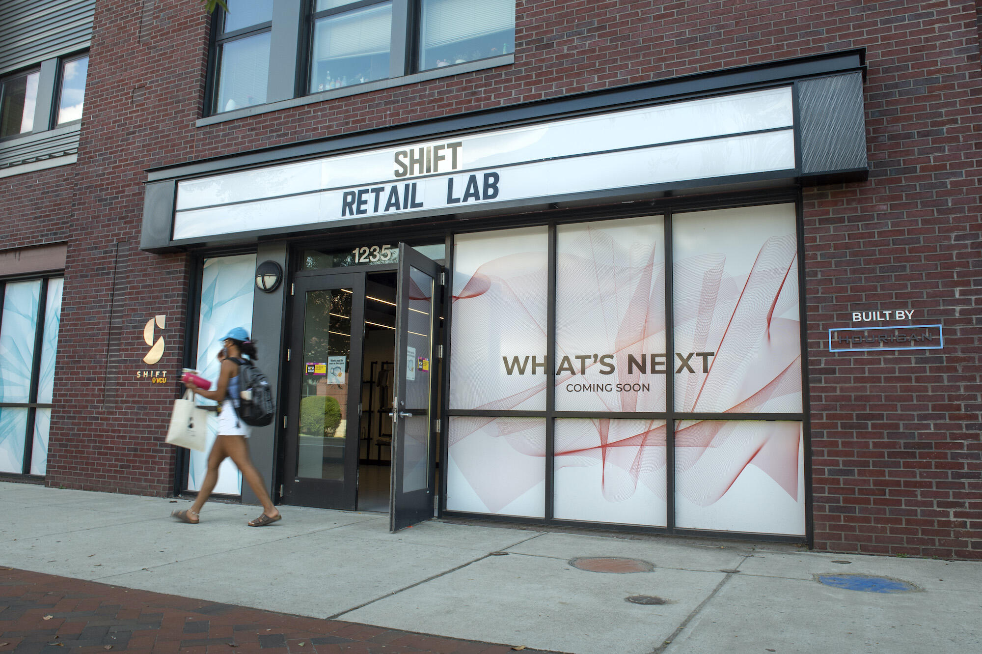 A photo of a woman walking past the Shift Retail Lab. 