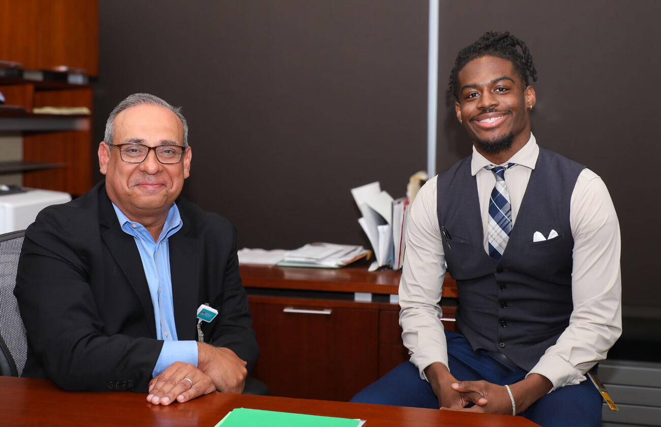 A photo of two men sitting at a desk. 